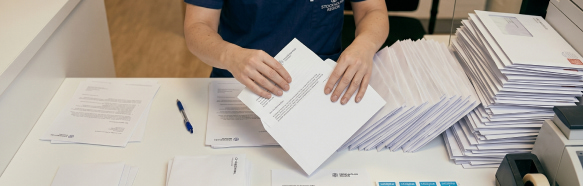 Sjukvårdspersonal hanterar pappersbrev och kuvert på ett skrivbord